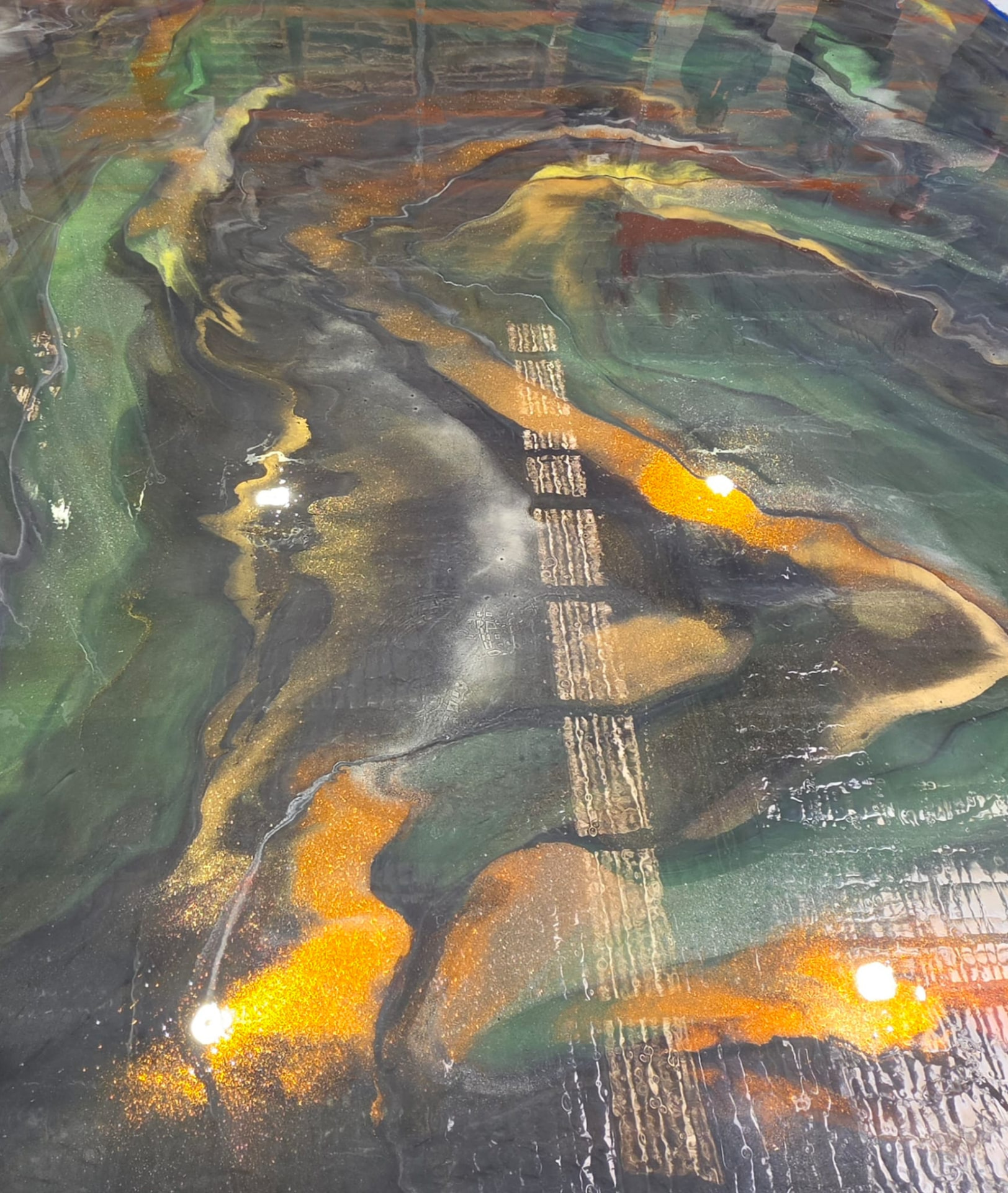 Metallic resin floor with gold veining running through green and graphite pigment