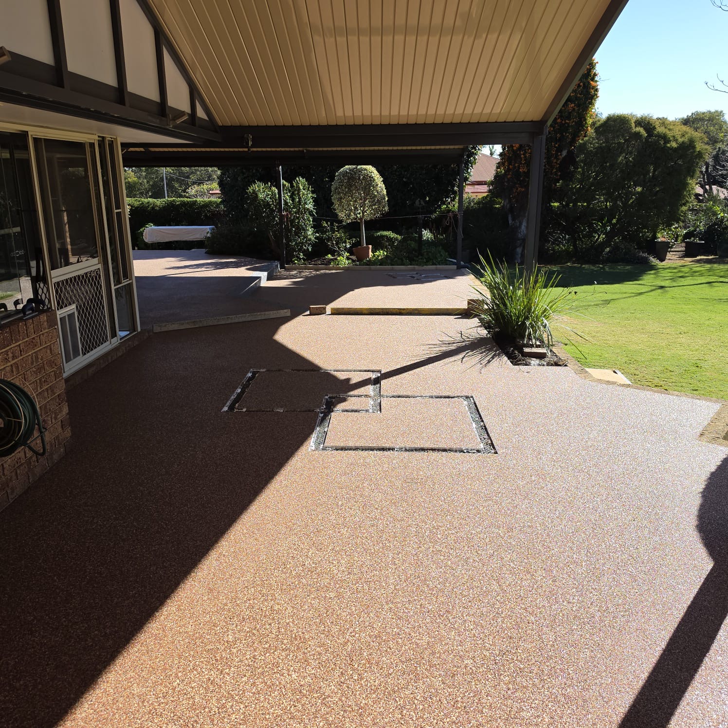 Terracotta resin bound surface wrapping around a home from patio to garden path