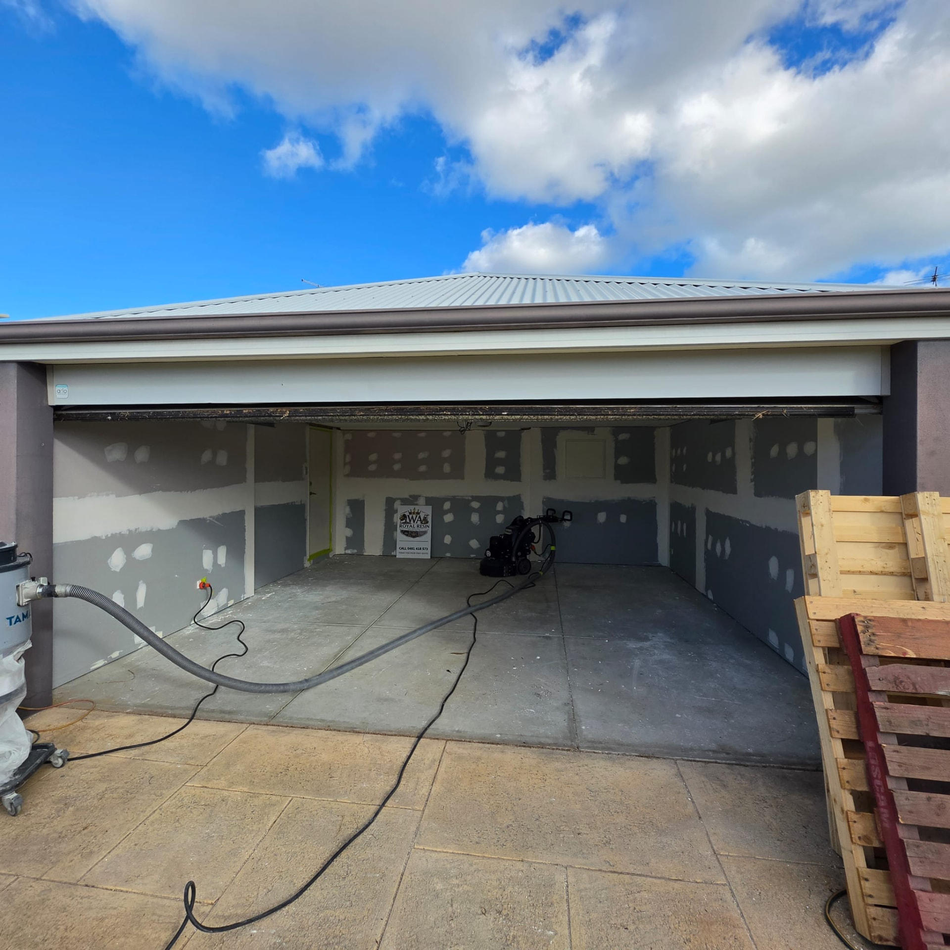 Garage with a bare concrete floor, grinder and dust extraction set up ready for coating