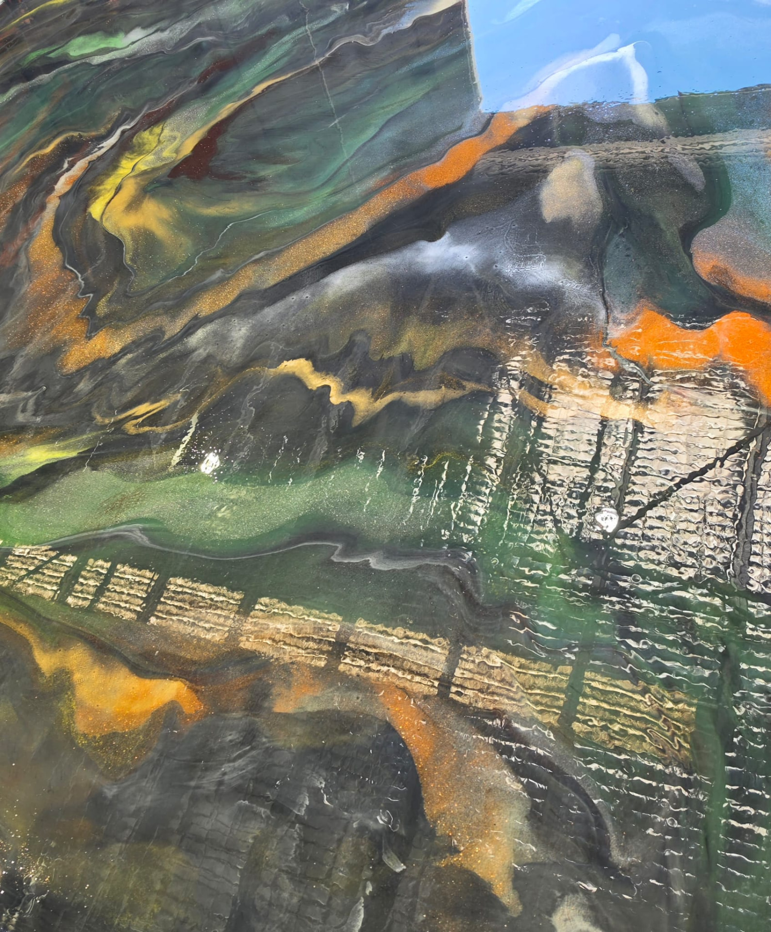 Wide metallic epoxy resin floor in green, orange and black with a wet-look finish
