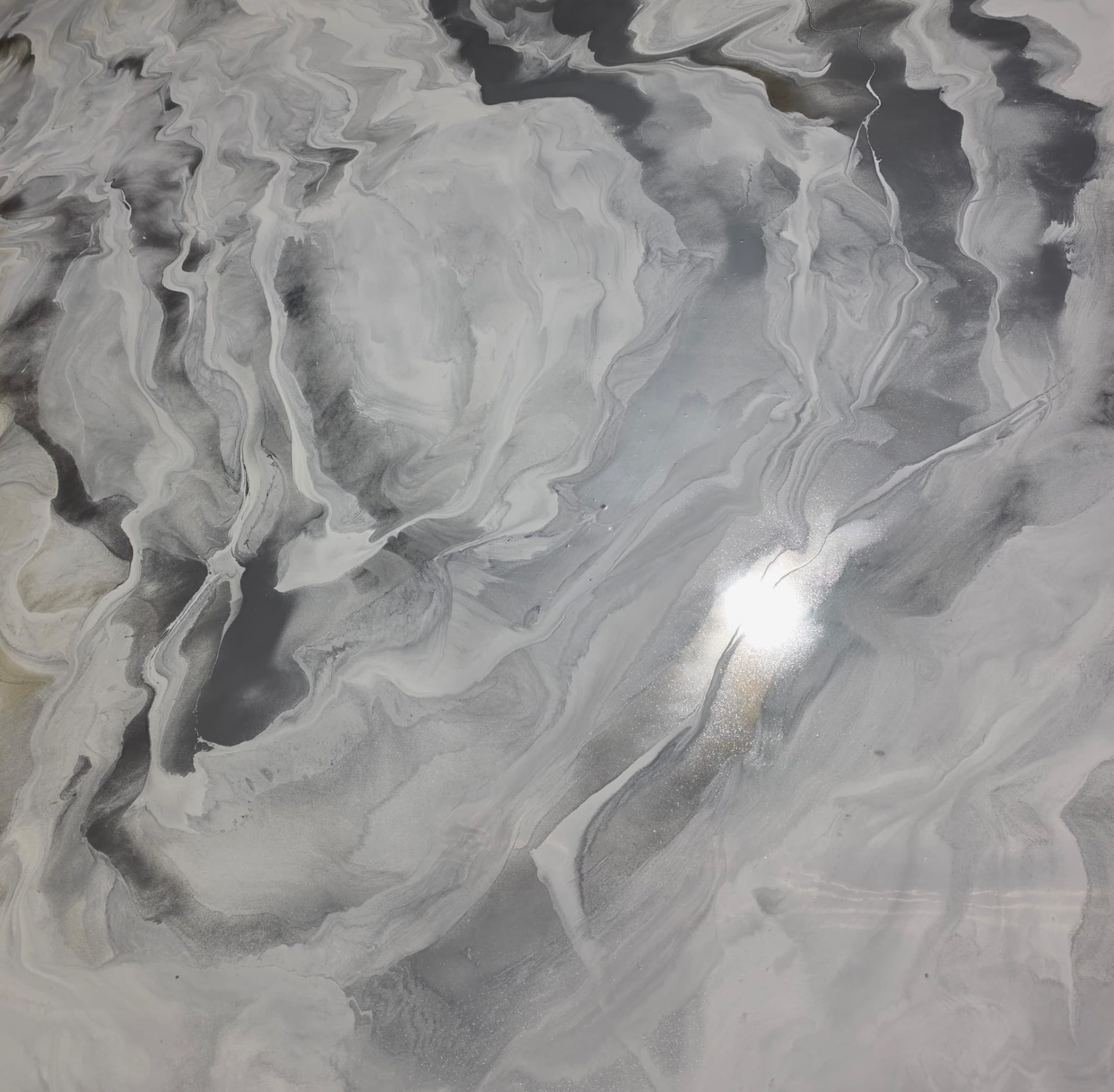 Silver and black marbled metallic epoxy floor with a bright light reflection